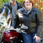 barbara leaning against her motorcycle with her husband