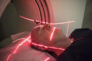 Male patient lying in medical scanner with red lights shining on face and head